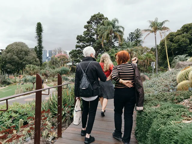 Three people walking in botanical gardens.