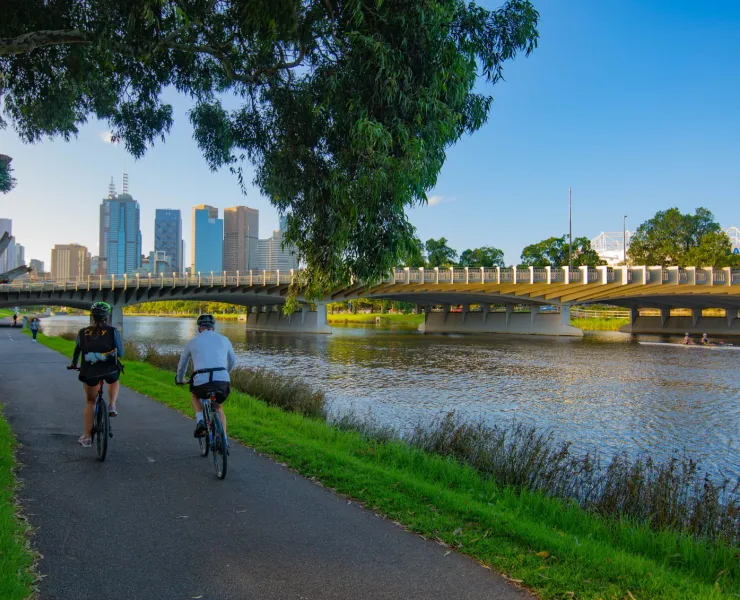Two cyclists riding on a bike path by a river.