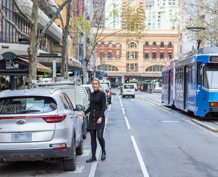  A person getting into their car which is parked along a busy street in the city.