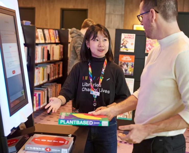 Library staff explaining how the self-borrowing machines work at the library
