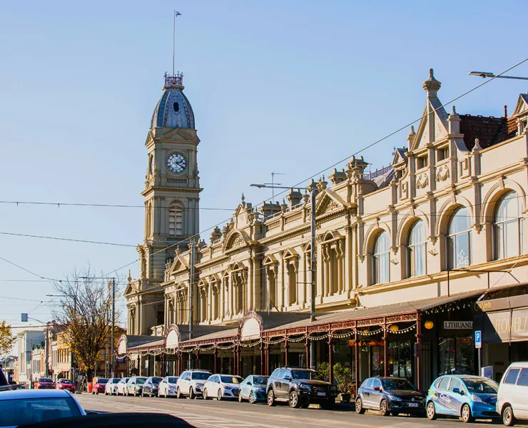 Street scene with a town hall clock tower and row of historic building shopfronts.
