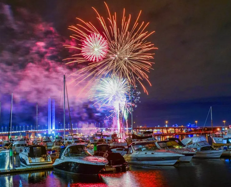 Iridescent fireworks exploding over a line of berthed vessels