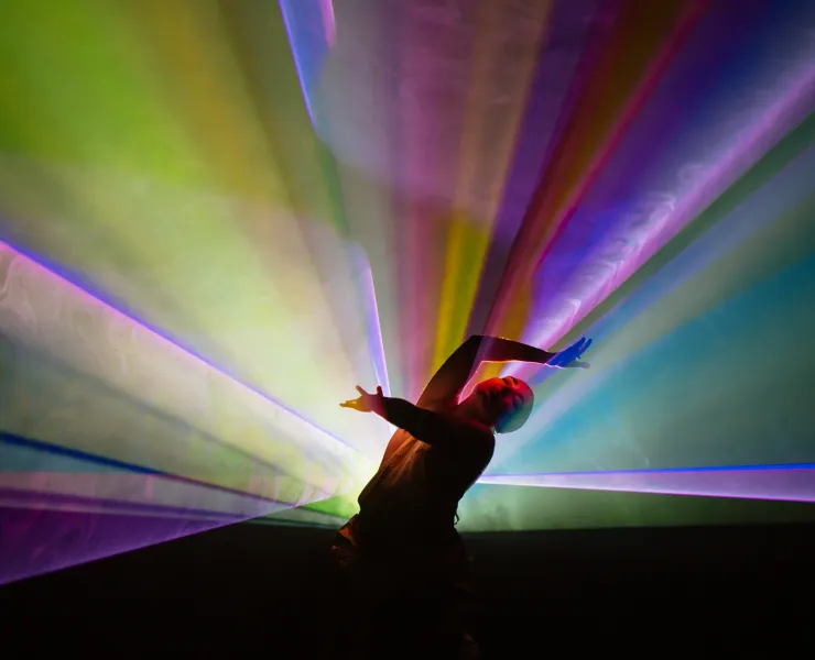 A man dancing in rainbow light projection