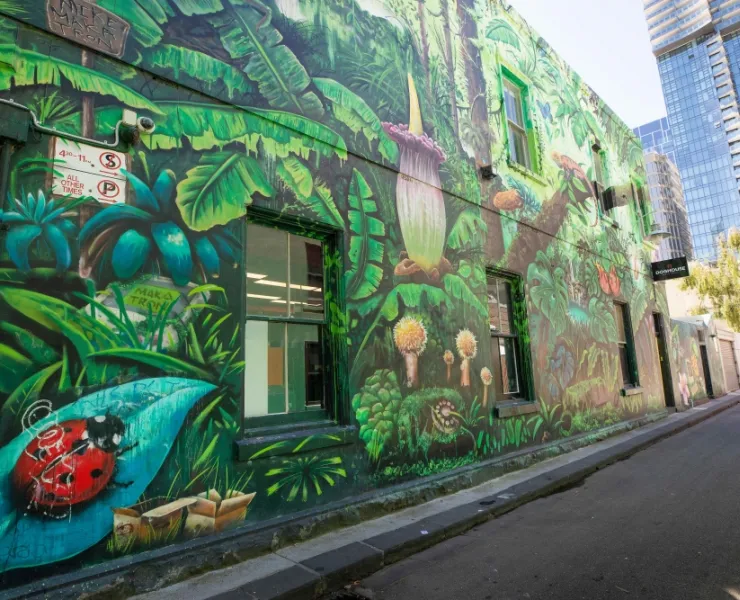 Art on a building featuring tropical plants and a ladybird on a leaf