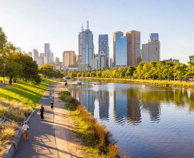 People walking along river path with skyline in the background