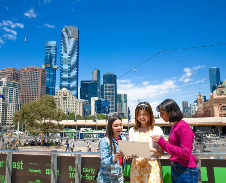 International students looking at laptop in front of city skyline