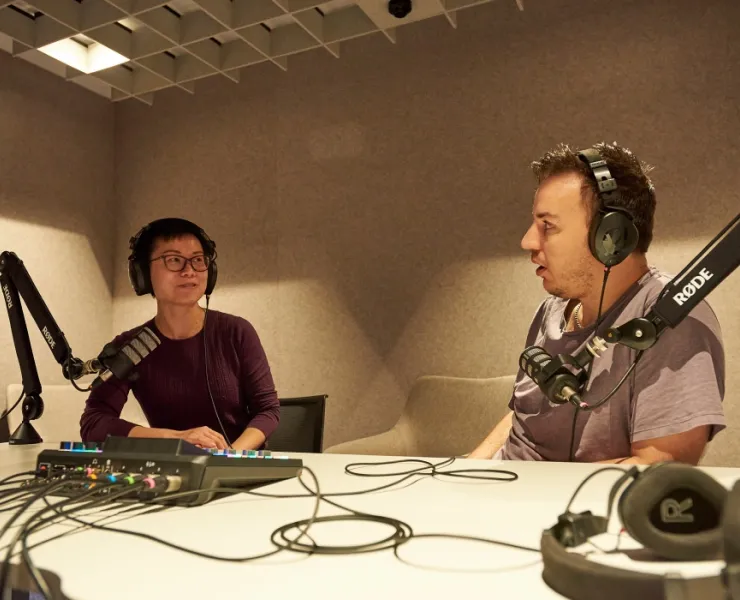 Woman and man with headsets on recording podcast in studio