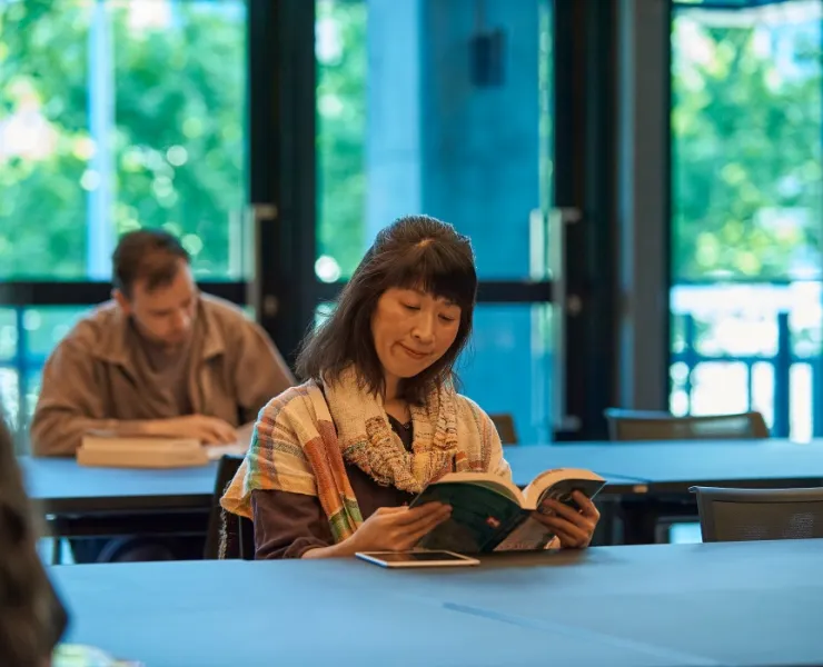 Woman reading book at library table