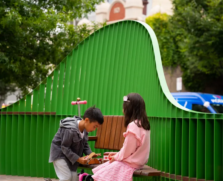 Two children playing at a social space near a fence
