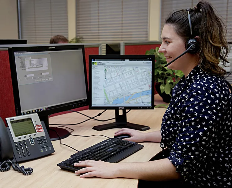 A customer service staff member answering calls and using a computer.