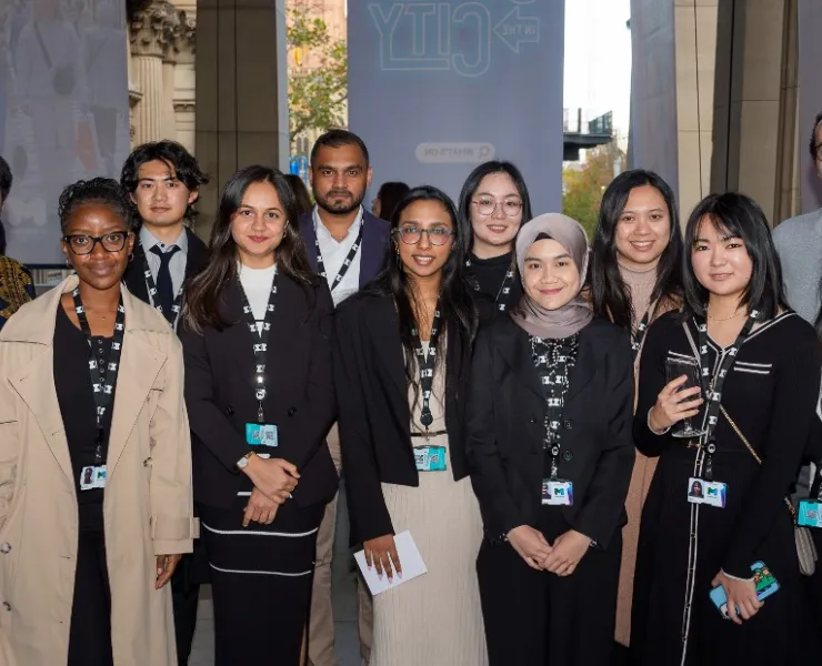 A group of international students pose together for a photo. There are 12 people in total and most of them are wearing City of Melbourne lanyards.