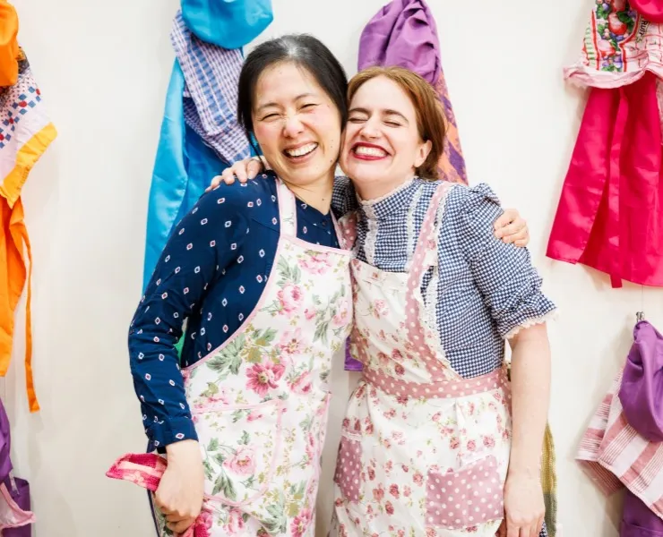 Two people wearing floral aprons posing for the camera