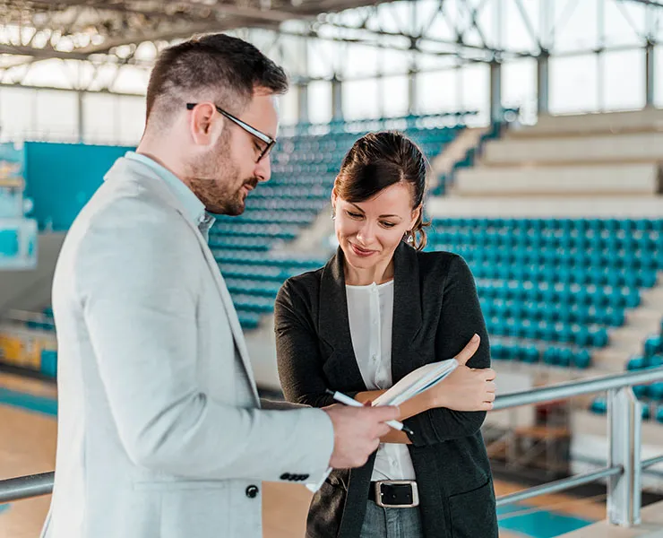 Woman and man looking at notebook, in indoor sports complex