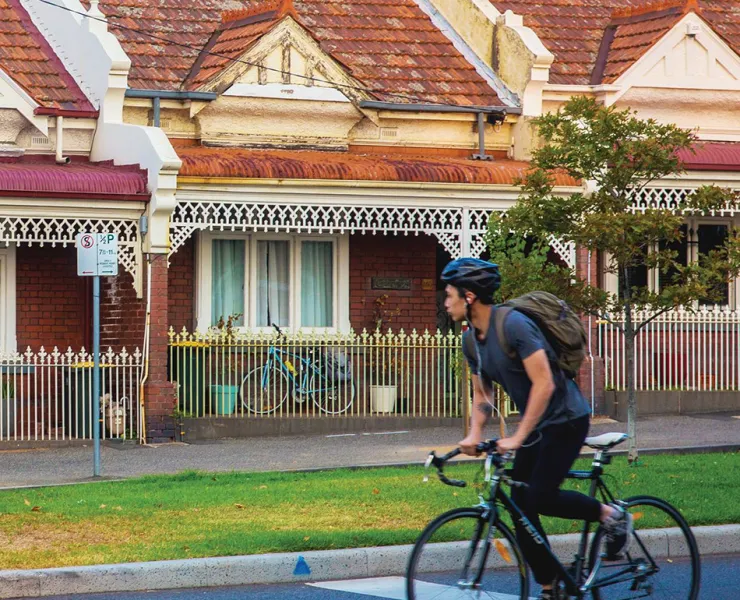 A person cycling past a row of terrace houses.
