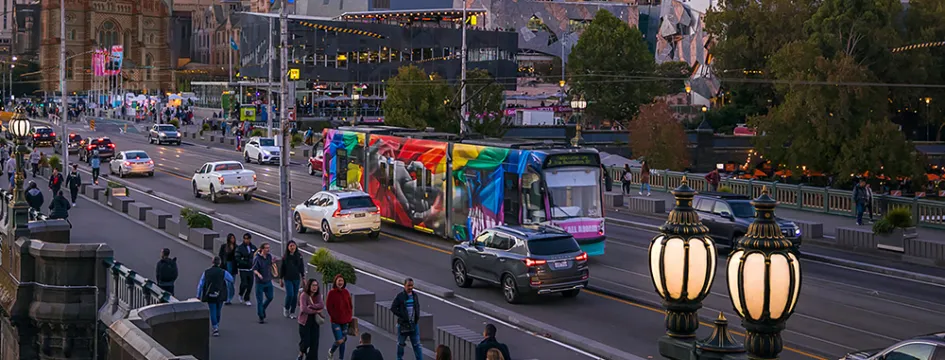 Pedestrians, cars and trams crossing a bridge near the city.