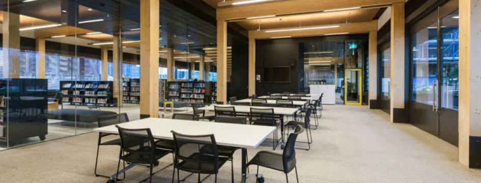A room with tables, chairs and bookshelves