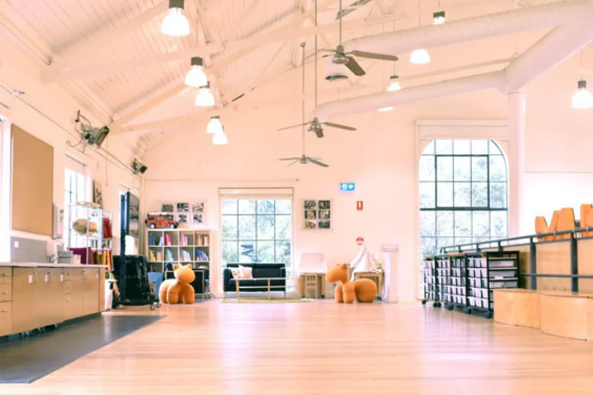A room with floorboards, high ceiling and rows of folded seats