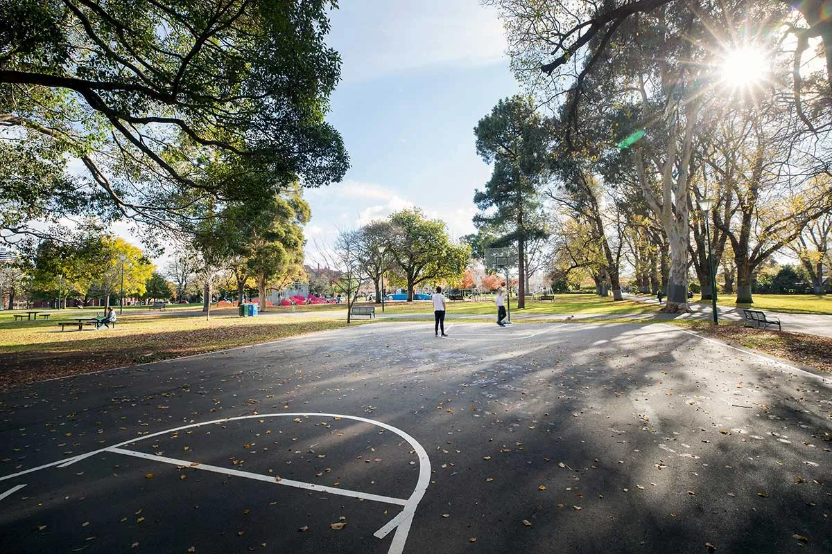 A basketball court surrounded by trees in a park