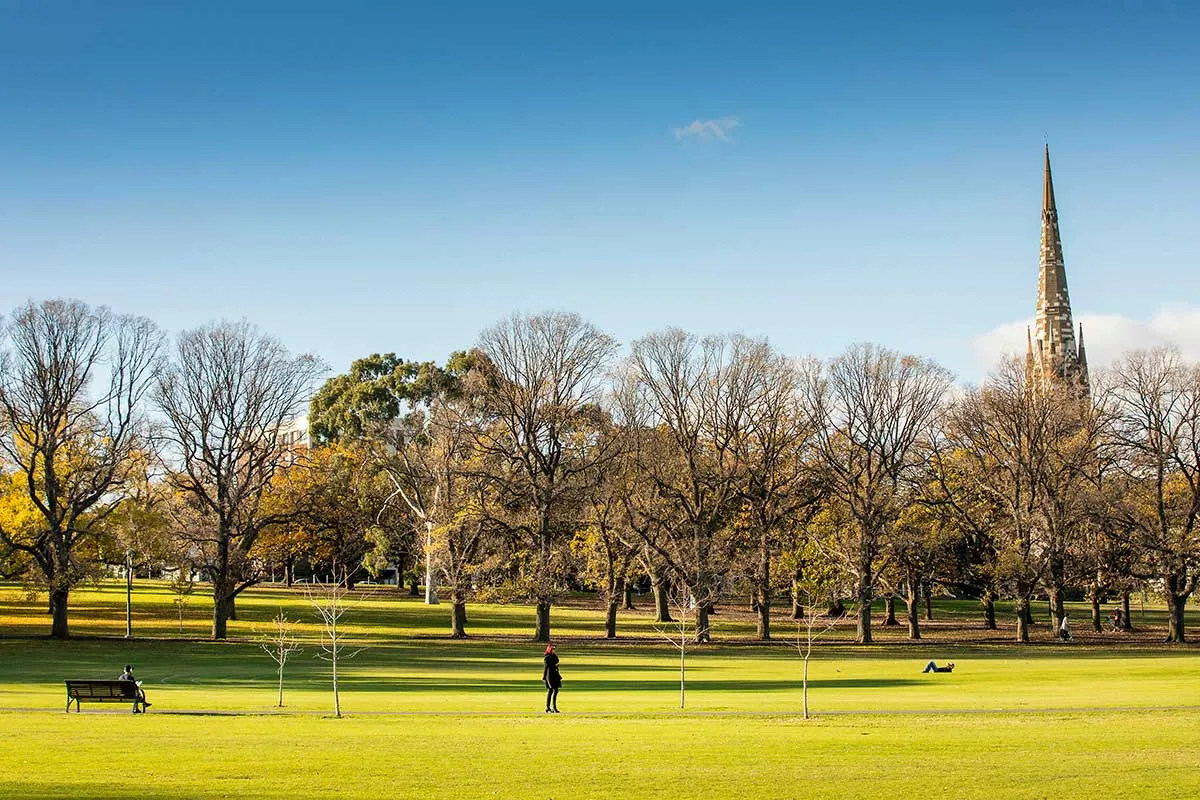 A green field in a park with a church spire in the background