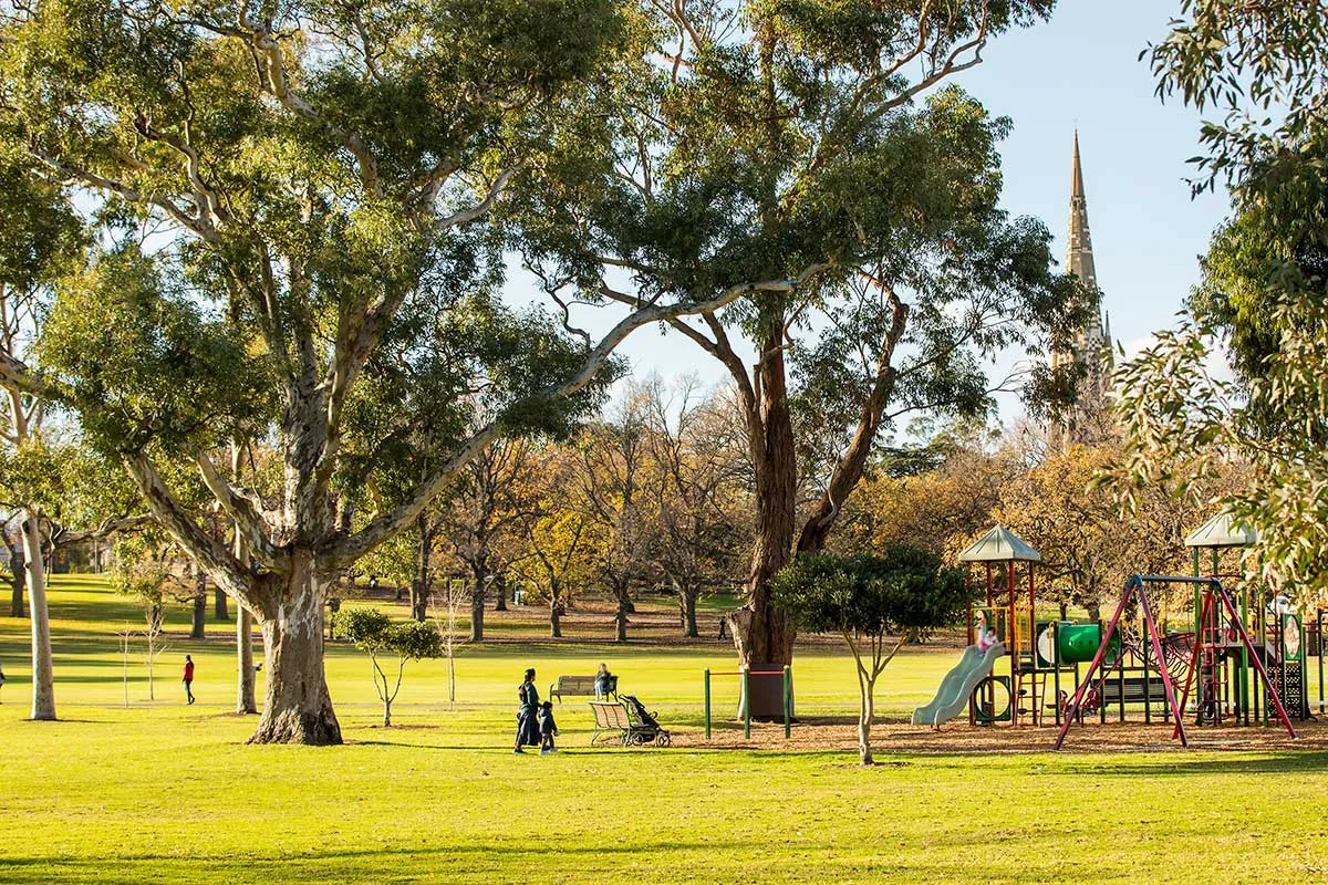 A park with a playground and church spire in the background