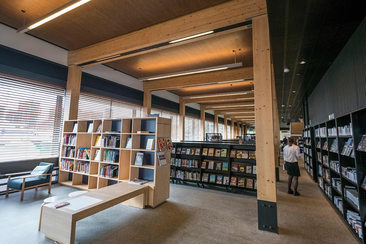 Rows of bookshelves in a space framed by wooden beams.