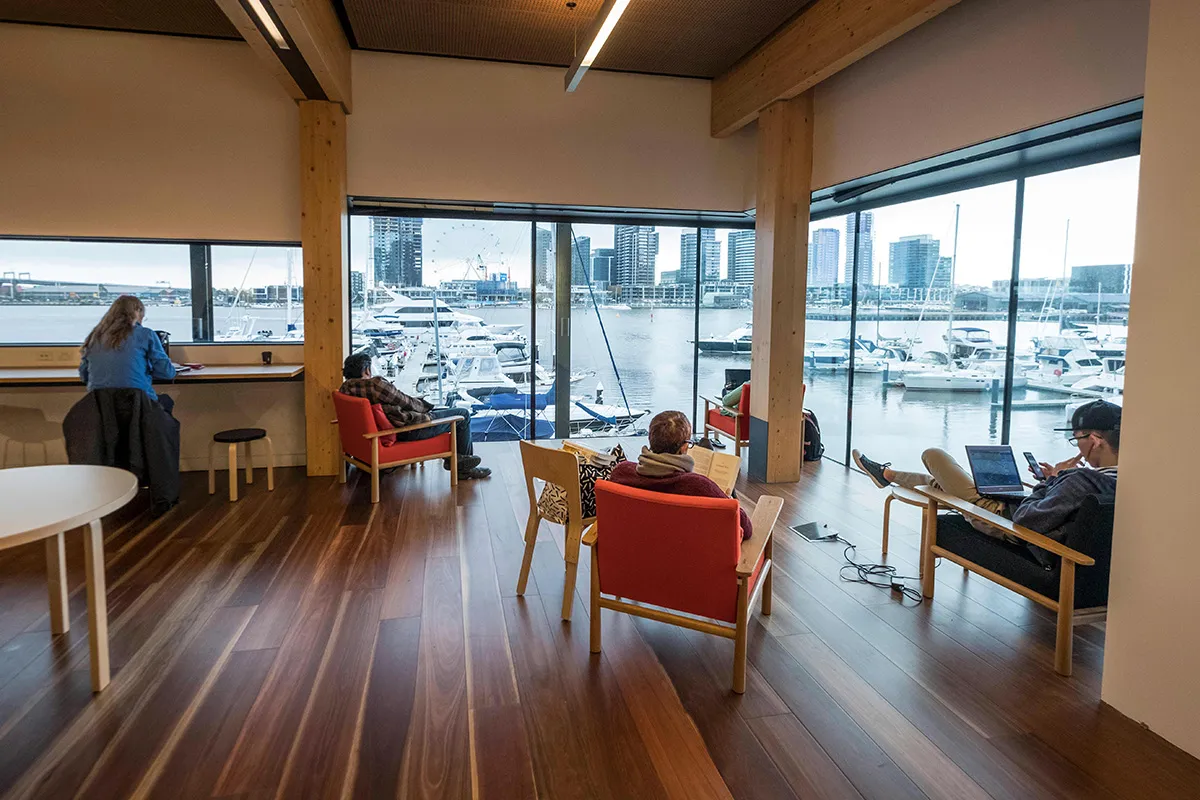 People studying and reading in armchairs in a corner with harbour views.