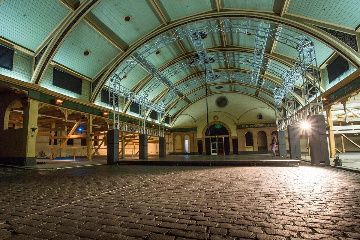 Large space with an arched roof and cobblestone floor.