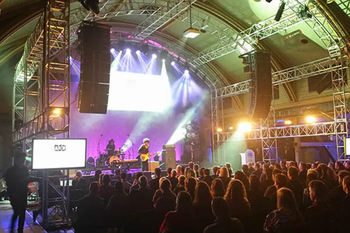 A band playing to a crowd in a small venue with arched roof.