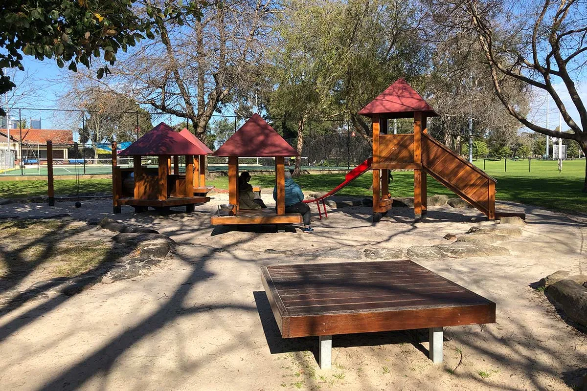 Wooden platform and play features with red roofs in a playground