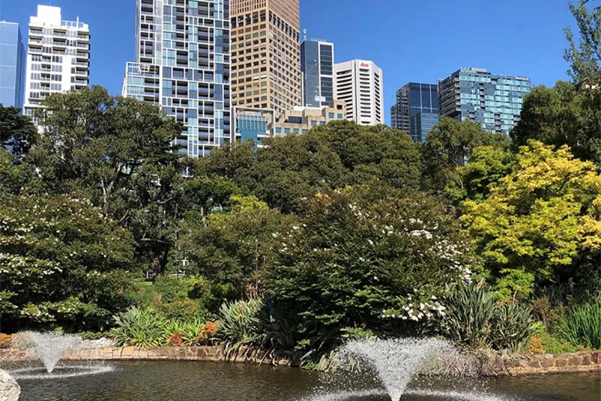 A fountain with trees and city buildings in the background