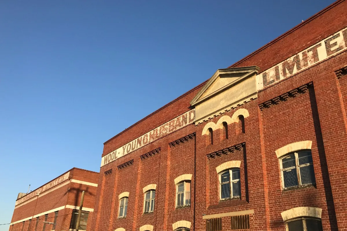 A historical building comprised of bricks. Text on top of the building reads "Wool Young Husband Limited."