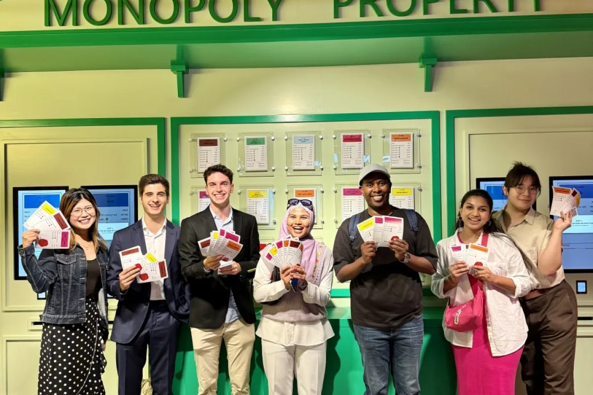 A group of people posing in front of a shop front with the title 'Monopoly Property'