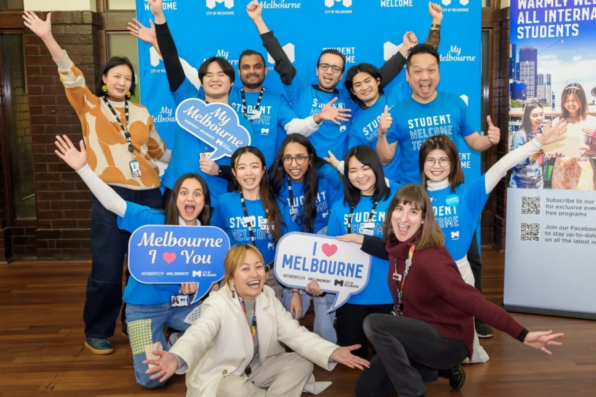 A group of people wearing blue shirts pose with signs that read 'Melbourne I love you', 'I love Melbourne' and 'My Melbourne'